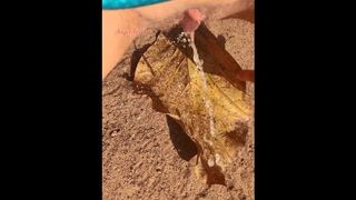 Girl Pissing on a large leaf that has fallen from a tree to the ground in Nature Park