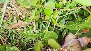 Village woman in a red tunic is pissing in the middle of a green field